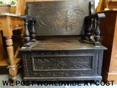 A carved oak monk's bench (H95 x W86cm x D43cm)