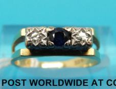 A yellow metal ring marked 18ct set with a sapphire flanked by diamonds (size J)