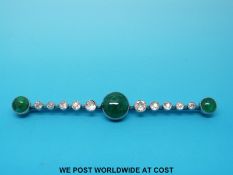 A platinum brooch set with three circular apple green emerald cabochons,