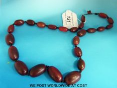 A rhinoceros horn or similar necklace consisting of 24 graduated ovoid beads, the largest 27 x 16mm,