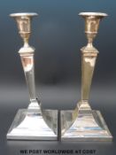 A pair of George V hallmarked silver candlesticks of square neoclassical form,