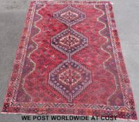A large woollen rug with three central graduated guls and geometric border on a red ground (270 x