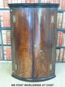 A Georgian flame mahogany bow-fronted corner cupboard with brass 'H' hinges (H108 x W71.