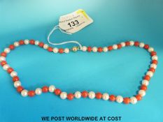 A necklace made up of alternating coral and pearl beads with a 14ct gold clasp