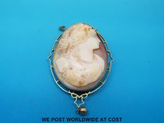 A yellow metal brooch/ pendant marked 9ct gold set with a cameo depicting a young lady