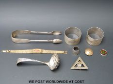 A pair of hallmarked silver napkin rings and a pair of silver sugar tongs,