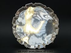 A hallmarked silver salver raised on four hoof feet B/ham, date rubbed but probably 1936,