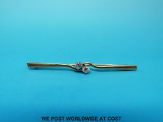 A yellow metal bar brooch marked 9ct set with two diamonds in a twist setting