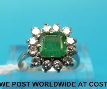 An 18ct white gold ring set with an emerald surrounded by diamonds (size K)