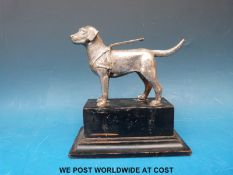 A plated model of a guide dog on wooden plinth,