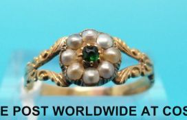 A Victorian ring set with a central emerald surrounded by seed pearls in a flower cluster with