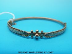 A hallmarked 9ct bangle with chased foliate decoration, Chester 1900 (5.