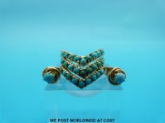 A yellow metal harem ring set with turquoise in a V shape with a pair of yellow metal earrings set