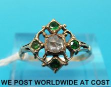 A yellow metal ring set with a rose cut diamond surrounded by emeralds (size M/N)