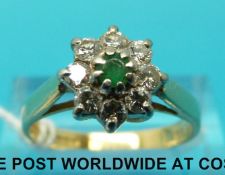 An 18ct gold ring set with a central emerald surrounded by diamonds (size O)
