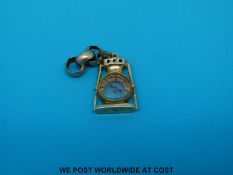 A hallmarked 10ct gold charm in the form of a lamp with a compass to the centre