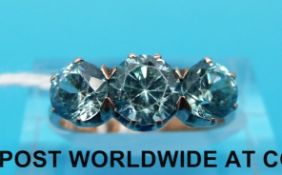 A yellow metal ring set with three round cut blue zircons (size K)