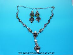 A silver necklace set with various gems to include garnets, pearls and amethysts,