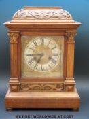 An electrified mantel clock in carved case and brass spandrelled dial