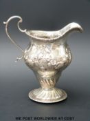 A Georgian hallmarked silver embossed cream jug,