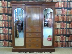 An Art Nouveau mahogany double wardrobe with an arrangement of two bevelled mirrored doors opening