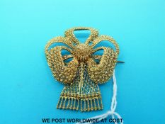 A Victorian filigree brooch in the shape of a stylized bow with a small compartment to the back