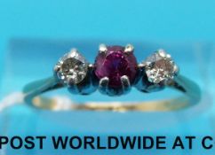 A yellow metal ring marked 18ct set with a ruby flanked by diamonds (size K/L)