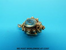 An 18ct gold charm with filigree decoration set with three oval blue topaz