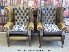 A pair of leather Chesterfield wing back armchairs with button back and metal stud decoration,