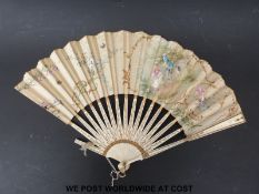 A late 19thC fan with gilt decoration of a couple in garden,
