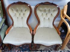 A pair of mahogany framed balloon backed nursing chairs with carved detail and button backs