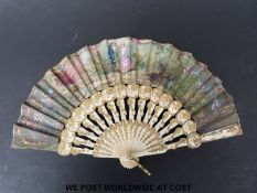 A late 19thC fan with bone and gilt decorated sticks and painted scene in a box of a couple sitting