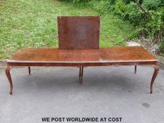 A very large burr walnut veneered extending dining table with carved decoration,