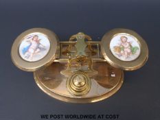 A set of brass postage scales with ceramic plaques of cherubs to the pans and stack of weights to