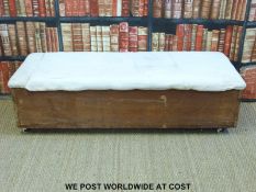 A pine ottoman with upholstered top raised on castors (L148cm)