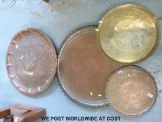 Four copper and brass trays including a large crimped edge example (largest 72cm diameter)
