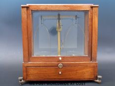 A set of small cased laboratory scales with drawer below containing various weights including