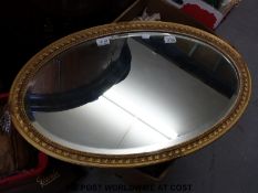 A gilt framed oval bevelled edge mirror (H47 x W75cm)