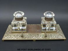 A Victorian brass inkwell with embossed decoration and cut glass inkwells