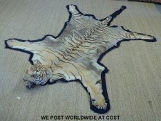 A late 19th or early 20th century taxidermy tiger skin with head mounted on cloth backing with felt