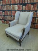 An upholstered wingback armchair with carved oak frame