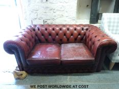 A red leather two seat Chesterfield sofa