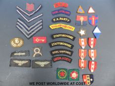A quantity of various military cloth badges including shoulder flashes,