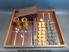 A chess and backgammon box containing two 19thC Lignum Vitae dice shakes, draughts set,