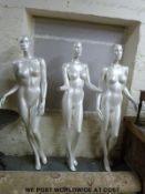 Three modern full length shop display mannequins on glass circular bases