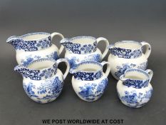 A set of six graduated blue and white jugs