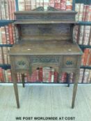 An oak bonheur du jour with carved decoration raised on tapered legs,