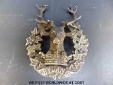 A white metal Bydand Gordon Highlanders badge