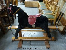 A vintage rocking horse with black coat, blonde mane and tail and red tack,