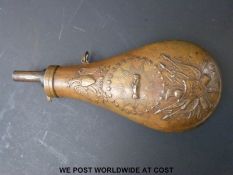 A copper powder flask with embossed decoration of a US crest with shaking hands and eagle above,